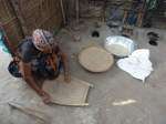 Cette femme qui y vit passe au tamis la terre ramassée près de camions chargeant des sacs de riz pour récupérer les grains mangeables (19/20)